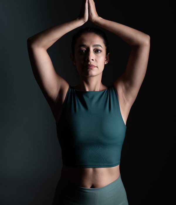 Woman performing a calm yoga pose in a dark room with jade green light.